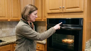 Homeowner using a smart oven touchscreen while experiencing display and control panel issues in a Naperville IL kitchen